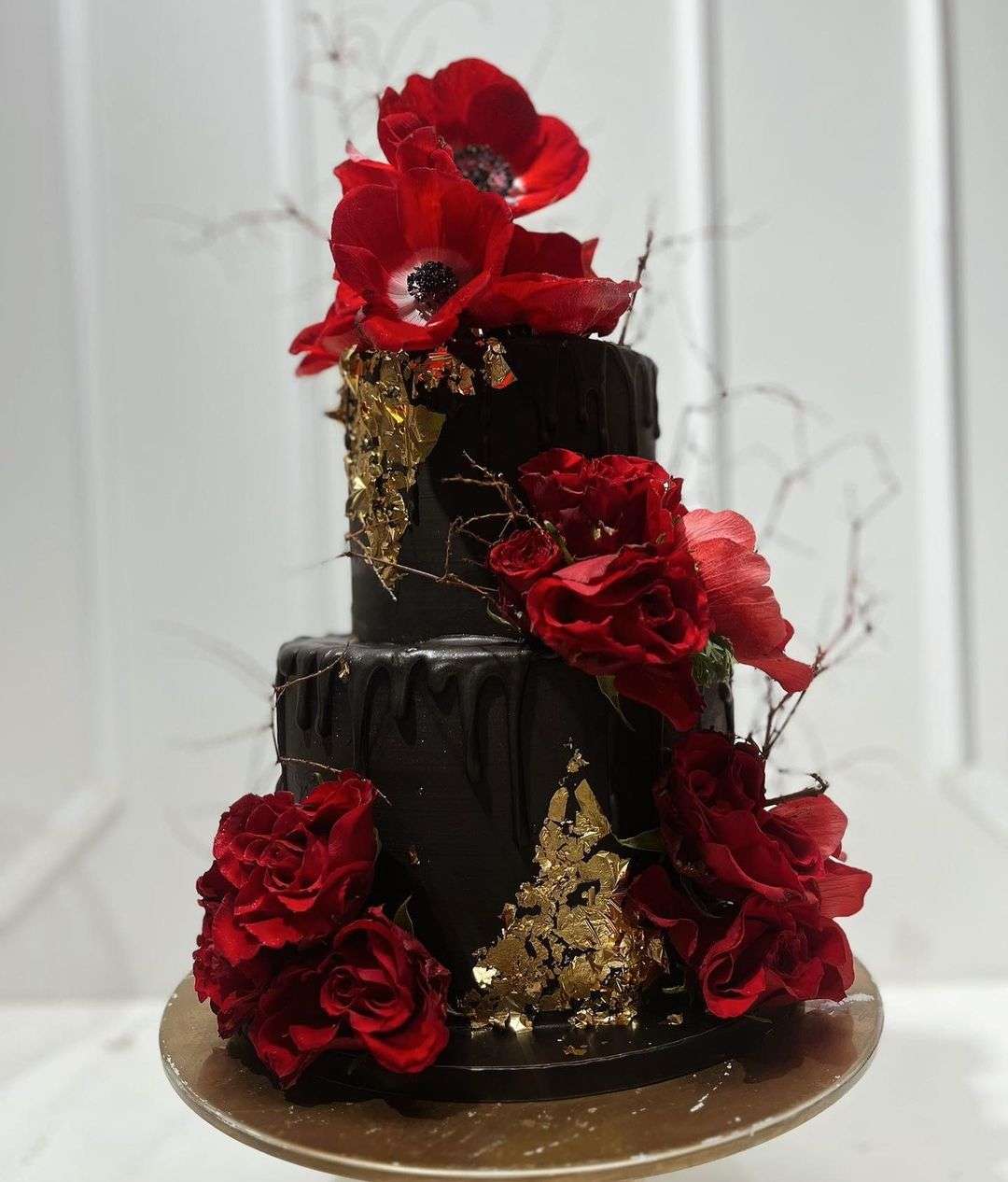 black wedding cake with gold foil and red flowers via magnoliaslastice.cakes
